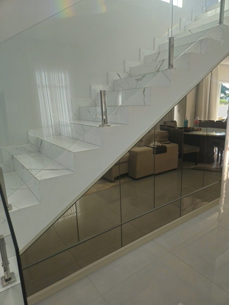 Mirrored storage cabinets built into the space beneath white marble stairs.