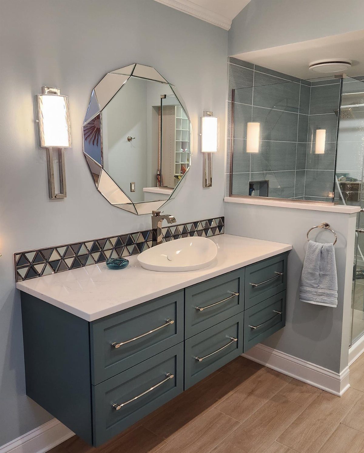 Blue floating bathroom vanity with white countertop and geometric tiled backsplash.
