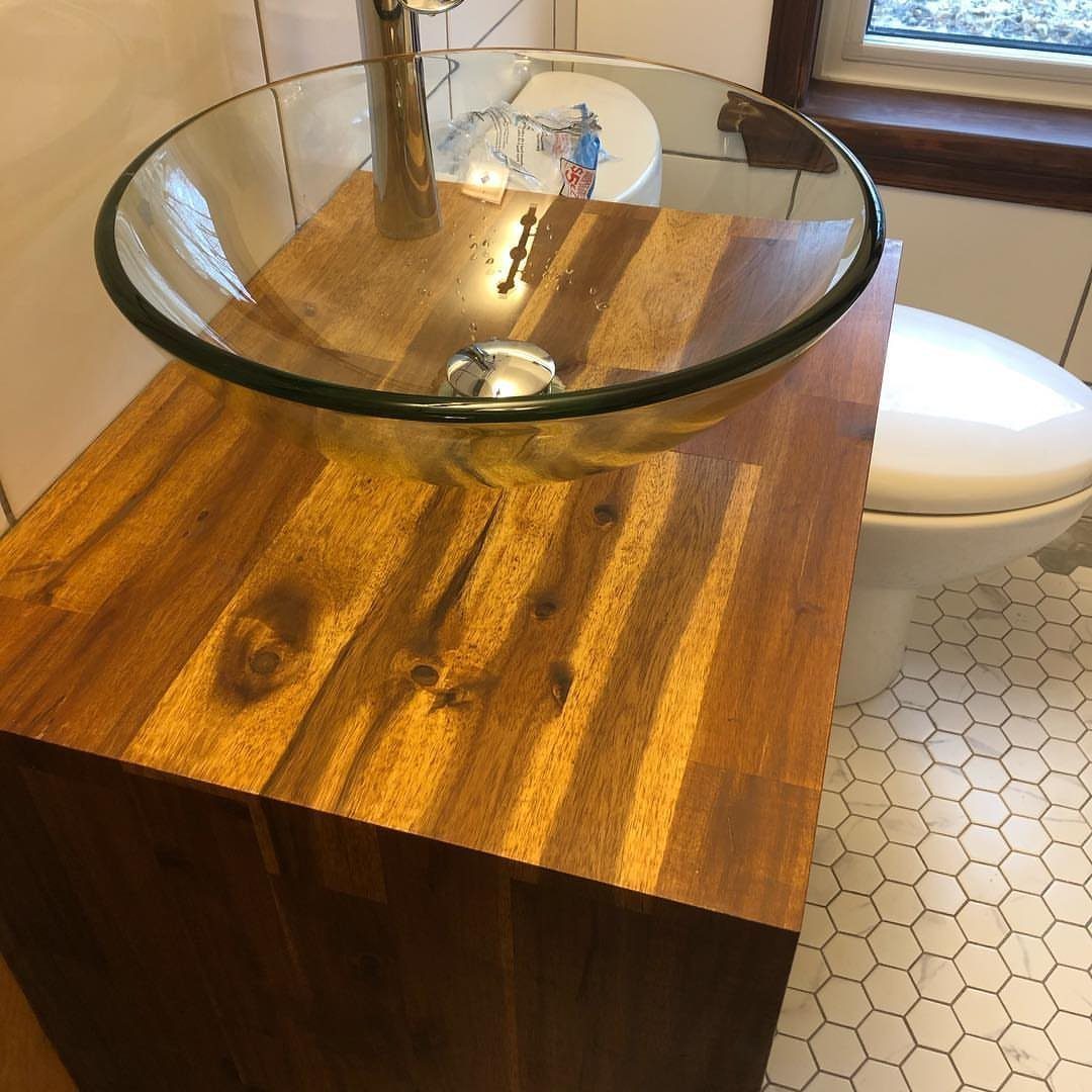 Glass vessel sink on a dark wood vanity with white hexagonal floor tiles.