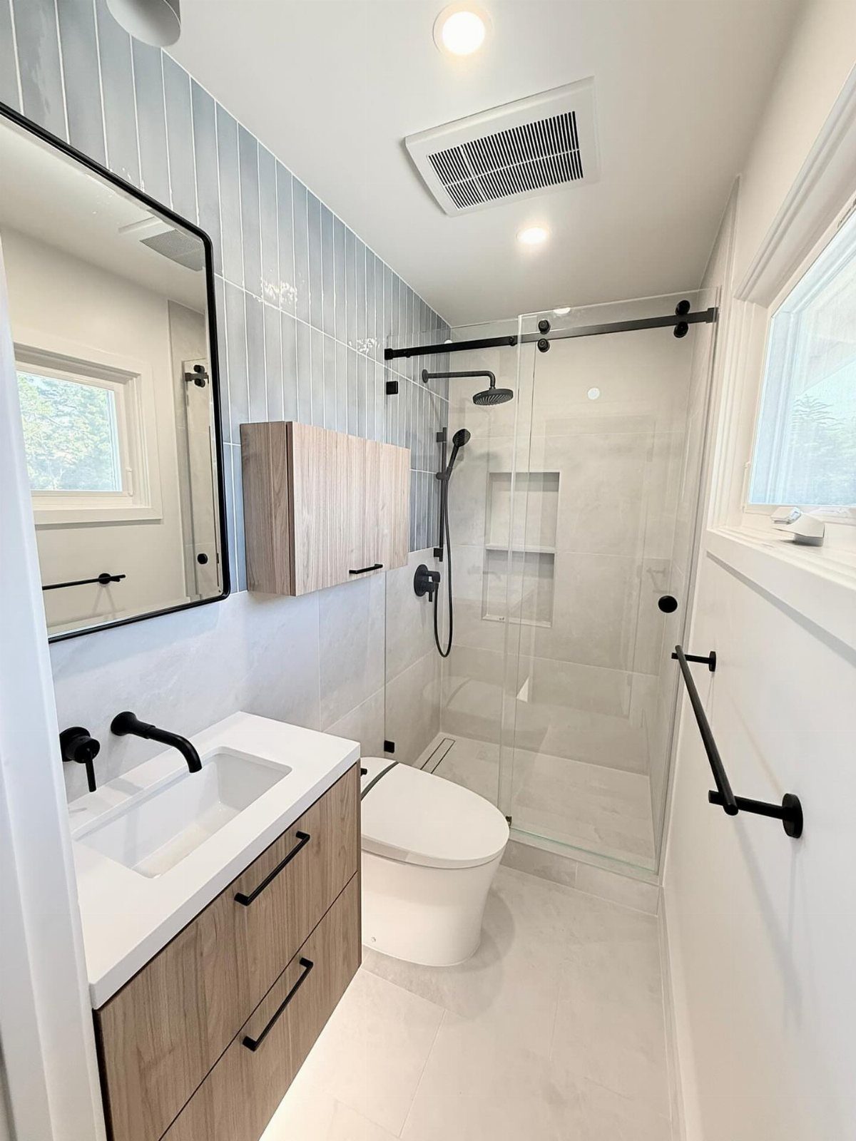 Light wood bathroom vanity with white sink and black fixtures in modern bathroom