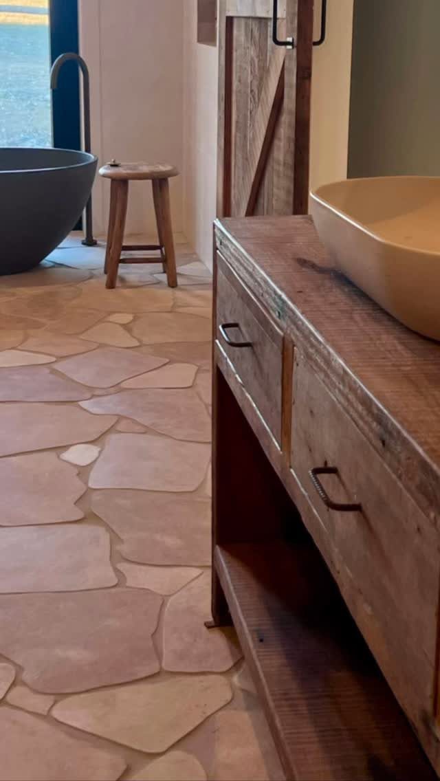 Rustic wooden vanity with a tan vessel sink and open bottom shelf storage.