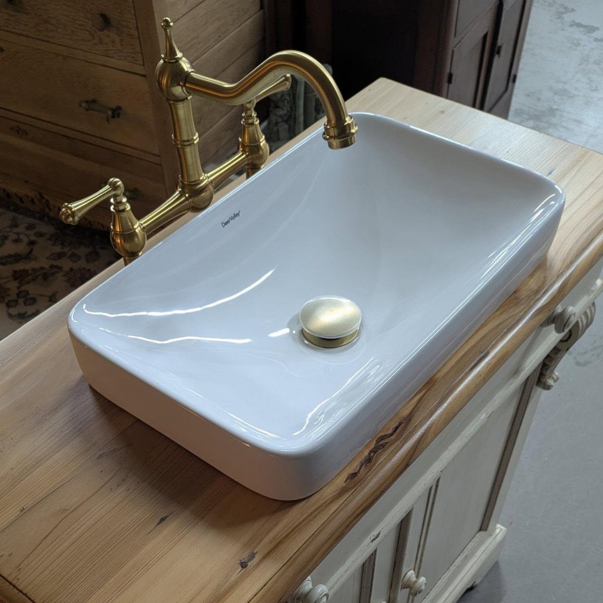 White rectangular vessel sink with gold faucet on a light wood vanity