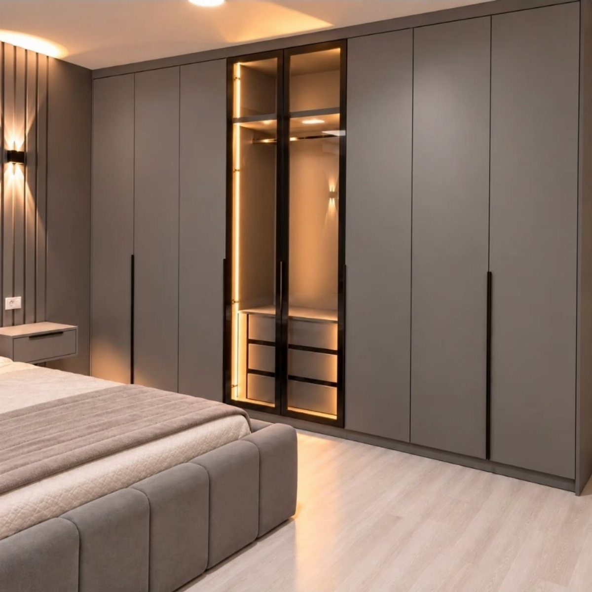 Grey floor-to-ceiling built-in wardrobe with a glass-fronted section and warm interior lighting.