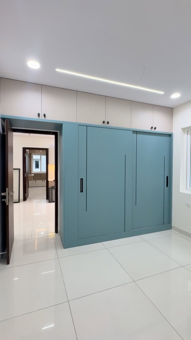 Light blue sliding closet doors with beige overhead cabinets and slim black handles.