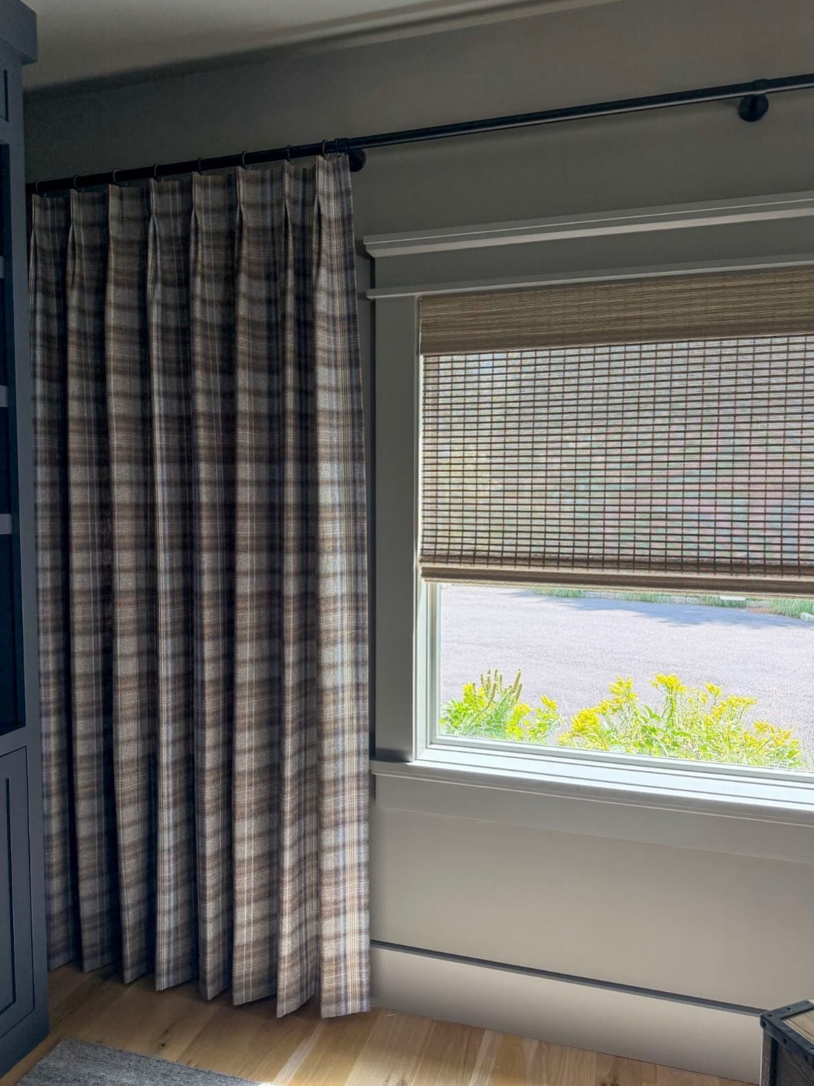 Plaid patterned curtains and a woven bamboo shade on a living room window.