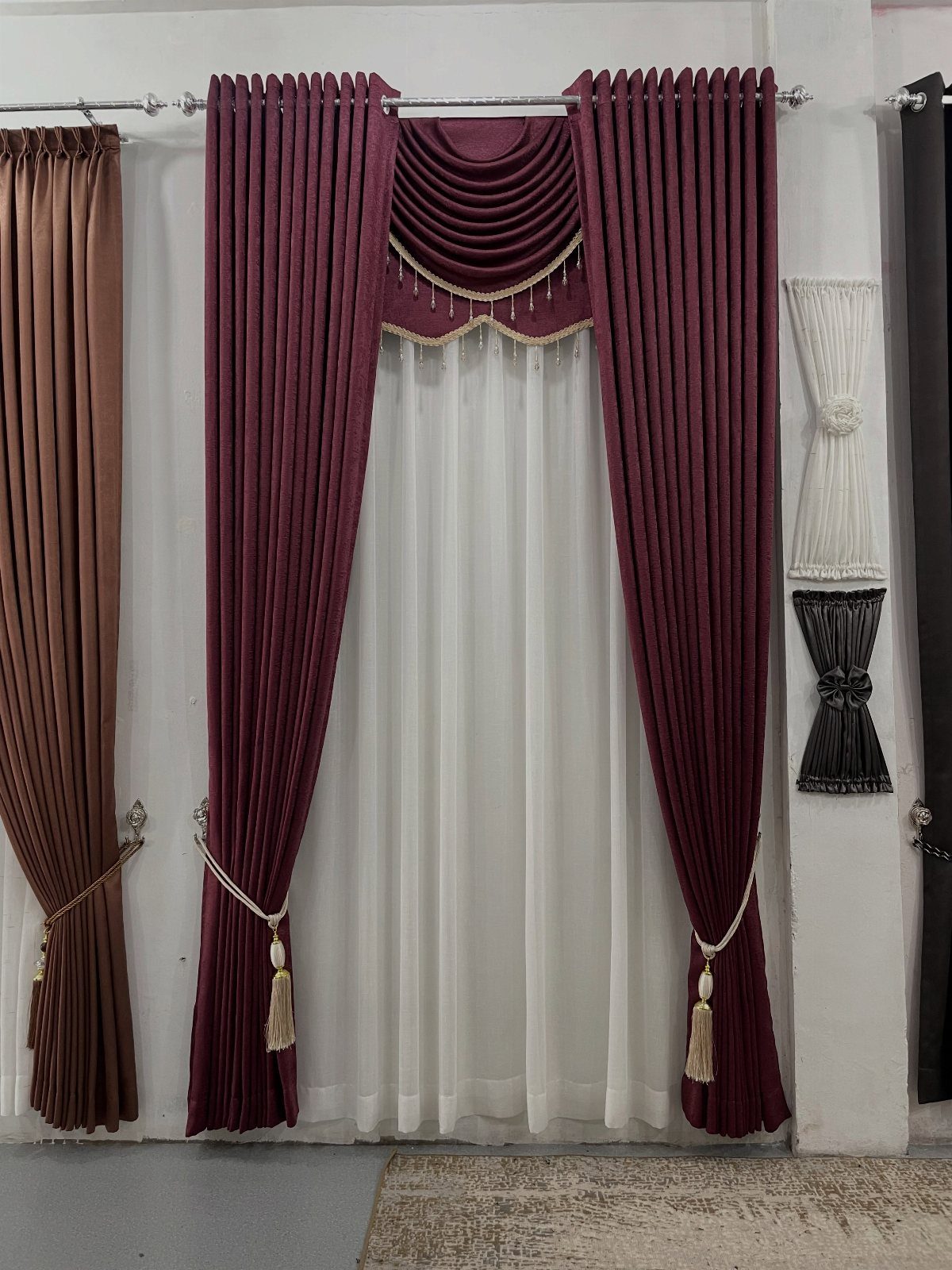 Maroon curtains with a draped swag valance and white sheer under-curtains.